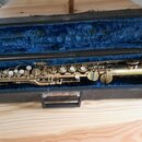 Zlatý sopránový saxofon v černém kufru s modrým vnitřkem. Nástroj vykazuje známky opotřebení povrchu a oxidaci kovu. Na těle nástroje nejsou žádné či…
