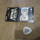 Sada kytarových trzelíků v originálním balení a jeden samostatný trzelík. Na černém obalu je bílý nápis METALLICA WHITE FANG CUSTOM FLIGHT PICK. Samo…