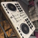 Bílý DJ controller s dvěma jogovými koly a ovládacími prvky. Na přístroji jsou viditelné nápisy Numark a MIXTRACK PLATTER. Povrch vykazuje známky pou…