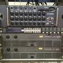 V racku jsou umístěna tři zařízení. V horní části je digitální mixér Midas MR18 s černým povrchem a řadou vstupních konektorů. Prostřední část tvoří…