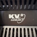 Detail černého plastového boxu s ventilačními otvory. Uprostřed je bílý nápis KV audio s malou číslicí 2 v kroužku a symbolem TM. Povrch plastu je te…