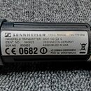 Detailní záběr na štítek ručního vysílače značky SENNHEISER. Na štítku je uveden text: HANDHELD TRANSMITTER SKM 100 G2 C, FREQ. RANGE: 740-776 MHz, I…