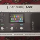 Fotografie zobrazuje krabici s multiefektovým procesorem HeadRush MX5. Na čelní straně krabice je nápis HEADRUSH MX5 a slogan THE MOST POWERFUL GUITA…