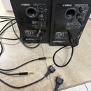 Dva černé aktivní reproduktory značky YAMAHA s nápisem POWERED SPEAKER SYSTEM MODEL HSS. Zadní strana obsahuje ovládací prvky LEVEL, vstupy INPUT a p…