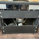 Zadní strana kytarového komba v černé textuře. Na horním kovovém panelu jsou nápisy FENDER MUSICAL INSTRUMENTS, CBS MUSICAL INSTRUMENTS a FULLERTON,…
