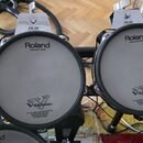 Dvě elektronické bicí pady značky Roland, model PD-85. Padu jsou bílé s nápisy „Roland“, „Head made by REMO“ a logem „V-Drums“. Pod logem V-Drums je…