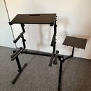 Černý kovový stojan s dvěma plochými deskami, pravděpodobně pro klavír nebo synthesizer. V horní desce je vyfrézovaný obdélníkový otvor. Konstrukce o…
