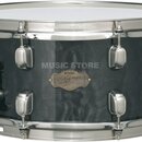 Černý snare drum s kovovým obručováním a chromovaným mechanismem. Na koruse je zlatý oválný štítek s nápisy „TAMA“, „Custom Superior“ a podpisem, kte…