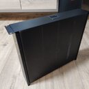 Černý, obdélníkový box z kovového materiálu s matným povrchem. Horní strana obsahuje jeden malý, obdélníkový výřez. Na povrchu jsou viditelné lehké š…
