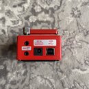 Zadní strana červeného efektového pedálu. Jsou zde viditelné konektory MIDI IN, MIDI OUT, DC IN a USB. U napájecího vstupu je nápis: DC IN USE BOSS P…