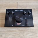 Černý zvukový interface M-AUDIO air 192|4. Na horní straně jsou čtyři otočné ovladače a uprostřed velký hlavní knoflík. Jsou zde nápisy CLIP, -3dB, -…
