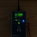 Šedý kovový efektový pedál s nápisem PROGRAMMABLE SOURCE AUDIO. Zařízení má v levé části zelený LED indikátor s označením frekvencí (63, 125, 250, 50…
