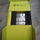 Žlutá kartonová krabice s nápisem GE3CC Amp modelling & Multi Effects. Uvnitř v černé pěnové výplni je umístěn stříbrný efektový pedál s několika spí…