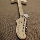 Světlá elektrická kytara s přírodním dřevěným povrchem. Na hlavě je černý nápis Squier STARCASTER a menší text BY FERNANDO. Nástroj vykazuje čistý po…