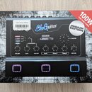 Fotografie zobrazuje krabici s kytarovým zesilovačem značky BluGuitar, konkrétně model IRIDIUM EDITION s výkonem 100W. Na předním panelu jsou vidět o…