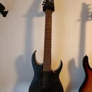 Černá elektrická kytara s tmavým dřevěným hnedým hmatníkem. Na hlavě je bílý nápis Ibanez. Kytara má dva humbuckery, jeden ovládací knoflík a černý m…