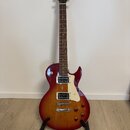 Elektrokytara s tónem sunburst v červeně a žluté, bílým pickguardem a dvěma humbuckery. Na hlavě je viditelné logo Cort a nápis CR-250. Nástroj je um…