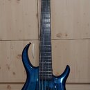 Modrá elektrická basová kytara s pětistrunným hmatníkem a dvoubarevným povrchem s viditelnou strukturou dřeva. Nástroj má dva humbuckery, tři ovládac…