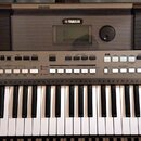 Šedý elektronický klavír s bílými a černými klávesami. Na horní části je uprostřed logo YAMAHA, displej a po obou stranách mřížkovité reproduktory. V…