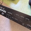 Zadní strana černého elektronického zařízení s nápisy ASR-X a ENSONIQ. Jsou zde viditelné konektory pro napájení, SCSI, MIDI (Thru, Out, In), Dual Fo…