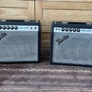 Dvě kytarové komba značky Fender v černé barvě s šedou síťovkou. Na ovládacím panelu obou přístrojů je nápis VIBRO CHAMP a logo Fender na přední stra…