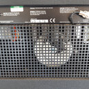 Zadní strana zesilovače s černou mřížkou a chladicím ventilátorem. Na horní části je bílý štítek s nápisy WARNING THIS EQUIPMENT MUST BE EARTHED, MOD…