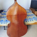 Zadní strana smyčcového nástroje, pravděpodobně violoncella, v hnědém dřevěném provedení. Povrch vykazuje známky opotřebení, zejména v dolní části ko…