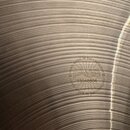 Detail kovového činely s koncentrickými rýhami na povrchu. Uprostřed je vyražené logo PAISTE obklopené nápisem MADE IN SWITZERLAND. Pod logem je uved…