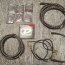 Sada příslušenství pro kytaru rozložená na šedém povrchu. Obsahuje šest balení stupenů s nápisem Ibanez GRIP WIZARD MADE IN JAPAN, krabičku strun Hea…