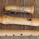 Dřevěná bloková flétra rozložená na tři části, položená na hnědé bambusové podložce. Na horní části je vyryto logo a nápis YAMAHA. Střední část obsah…