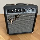 Kytarový kombo zesilovač s černým povrchem a stříbrnou textilní mřížkou. Na ovládacím panelu jsou nápisy INPUT, GAIN, VOLUME, TREBLE, BASS a POWER, p…