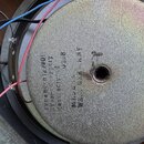 Fotografie zachycuje zadní část reproduktoru s kovovým magnetem v šedé barvě. Na povrchu magnetu je černý nápis: "type 86-n12/80!", "Year of producti…