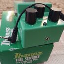 Zelený kytarový efekt s třemi černými ovládacími knoflíky a kovovým spínacím pedálem. Na krabici pod efektem je nápis Ibanez TUBE SCREAMER Overdrive…
