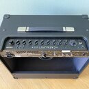 Kytarový kombo zesilovač v černém provedení s rukojetí na horní straně. Na ovládacím panelu je bílý nápis CATALYST 60 a logo LINE 6. Panel obsahuje ř…