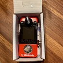 Červený kytarový pedál v bílém kartónovém boxu. Na přední straně je černý displej a nápisy IMPULSE, IR LOADER a tc electronic. V horní části je umíst…