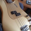 Zlatá elektrická basová kytara s čtyři strunami a dvěma černými snímači. Na těle je viditelné logo "Fender". Povrch laku vykazuje drobné oděrky a zná…