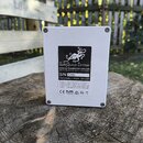Zadní strana bílého kytarového efektu v kovovém šasi. Na černé nálepce je logo s krakusem a nápisy EarthQuaker Devices, www.earthquakerdevices.com, 3…