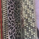 Detailní pohled na akordeon s bohatou ornamentikou. Nástroj má stříbrný kovový povrch s vyřezávanými rostlinnými vzory a řadu kulatých bílých tlačíte…