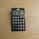 Černý přenosný sampler s LCD displejem, na kterém je nápis K.O! a dvě postavičky. V horní části je zlatým písmem nápis K.O! a logo. Zařízení obsahuje…