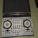 Bílý DJ kontrolér Traktor Kontrol S4 umístěný v hliníkovém transportním kufru s černou pěnovou výplní. Na zařízení je v levé horní části nápis TRAKTO…