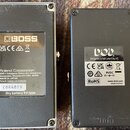 Fotografie zachycuje spodní strany dvou kytarových efektů. Levý pedál je stříbrný s nápisem BOSS a textem Roland Corporation, 2036-1 Nakagawa, Hosoe-…