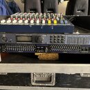 V černém transportním kufru se nachází mixovací pult a rackové zařízení. Spodní přístroj má nápisy dbx PROFESSIONAL PRODUCTS, DriveRack PA Compressio…