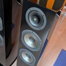 Dvě černé vysoké reproduktory s lesklým povrchem. Na přední straně pravého reproduktoru jsou tři jednotky: horní s nápisem „Cabasse“ a dvěma středním…