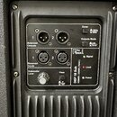 Záběr na zadní ovládací panel černého subwooferu. Jsou zde dva vstupy a dva výstupy typu XLR s nápisy Balanced Inputs a Balanced Outputs. Panel obsah…