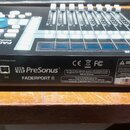 Černý kontrolér PreSonus FADERPORT 8 s modrými knoflíky a posuvníky. Na zadní straně jsou viditelné konektory Power, Footswitch a USB, značka PreSonu…