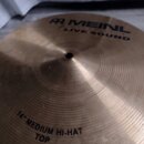 Kruhová mosazná činely s koncentrickým žebrováním. Na povrchu je černý nápis MEINL LIVE SOUND a v dolní části text 14" MEDIUM HI-HAT TOP. Povrch vyka…