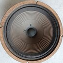 Kruhlový reproduktor s hnědou papírovou membránou a černým středovým prstencem. Membrana má koncentrické rýhy a v horní části jsou viditelné drobné o…