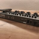 Šedý kytarový efektový procesor značky BOSS, model ME-80 COSM. Na zadní straně jsou viditelné konektory pro Guitar Input, L/MONO Output, Rec Out/Phon…