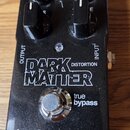 Kytarový efekt v černém kovovém šasi s kovovou stoupacíjkou. Na povrchu je bílý nápis tc electronic a model DARK MATTER DISTORTION. Jsou zde čtyři če…