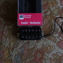 Černý humbucker s nápisem Seymour Duncan na spodní hraně. Vedle nástroje je červená krabička s nápisy Seymour Duncan a Invader™ Humbucker. Z pickupu…